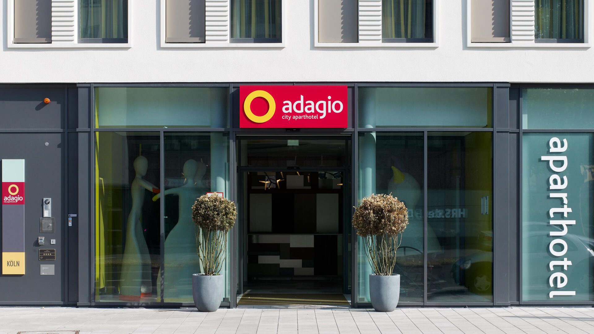 Eingang des Aparthotel Adagio mit Logo und bepflanzten Kübeln