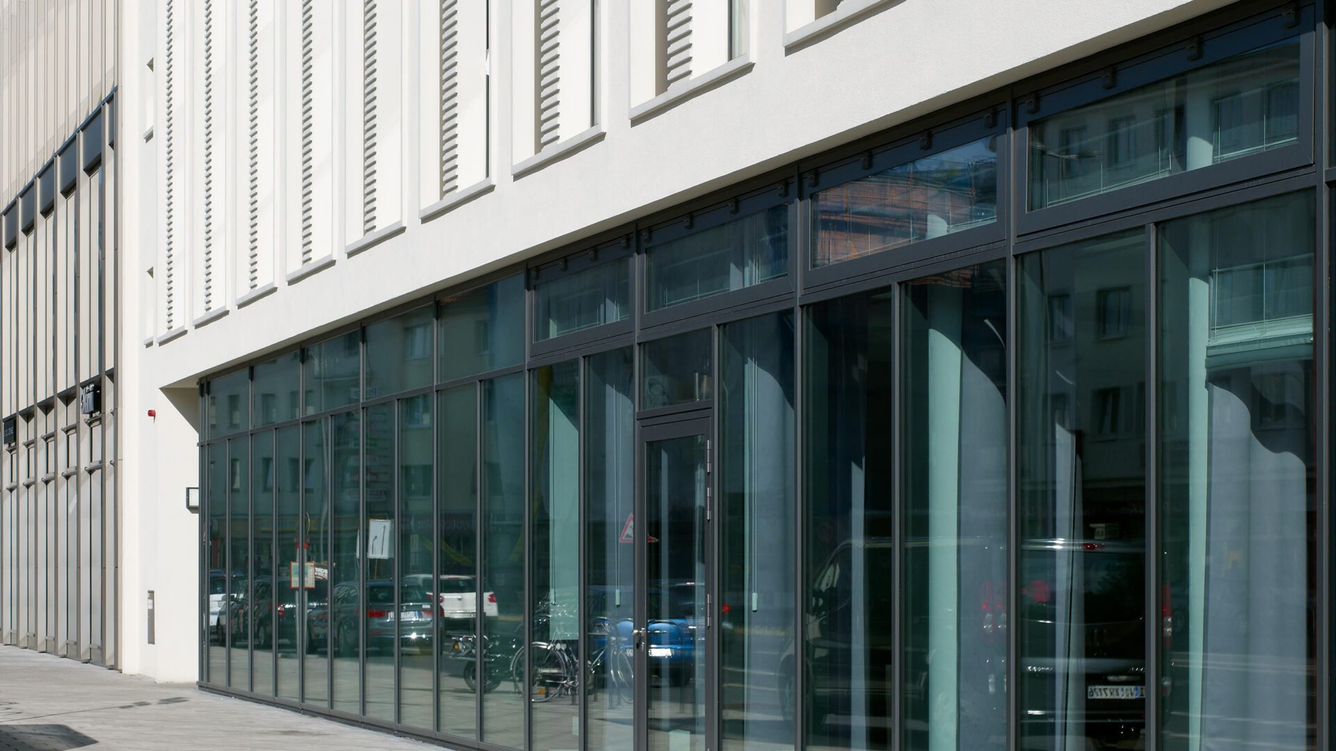 Verglaste Erdgeschosszone des Aparthotel Adagio entlang des Gehwegs