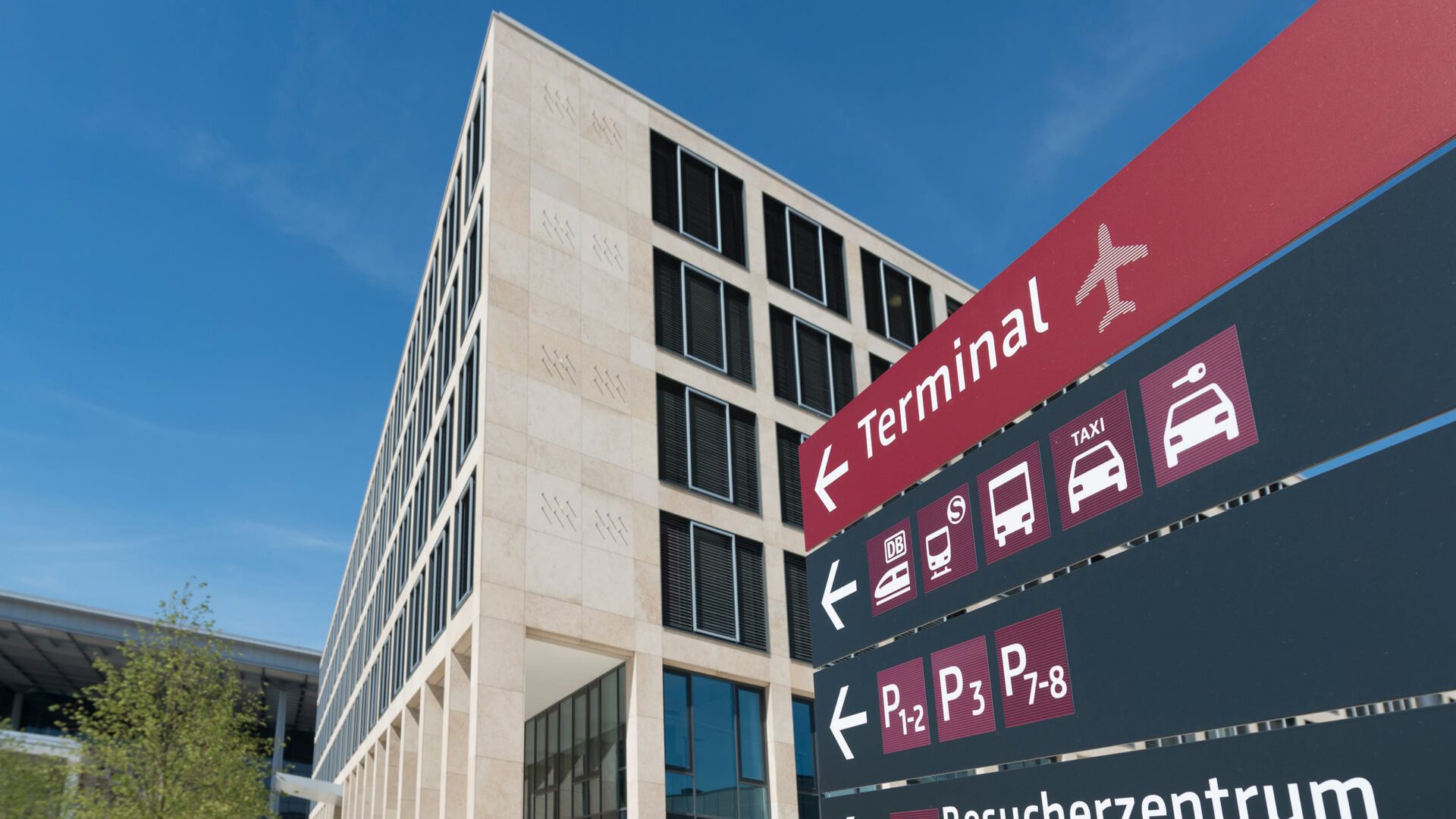 Fassade des Airport Center hinter dem Wegweiser zum Flughafenterminal