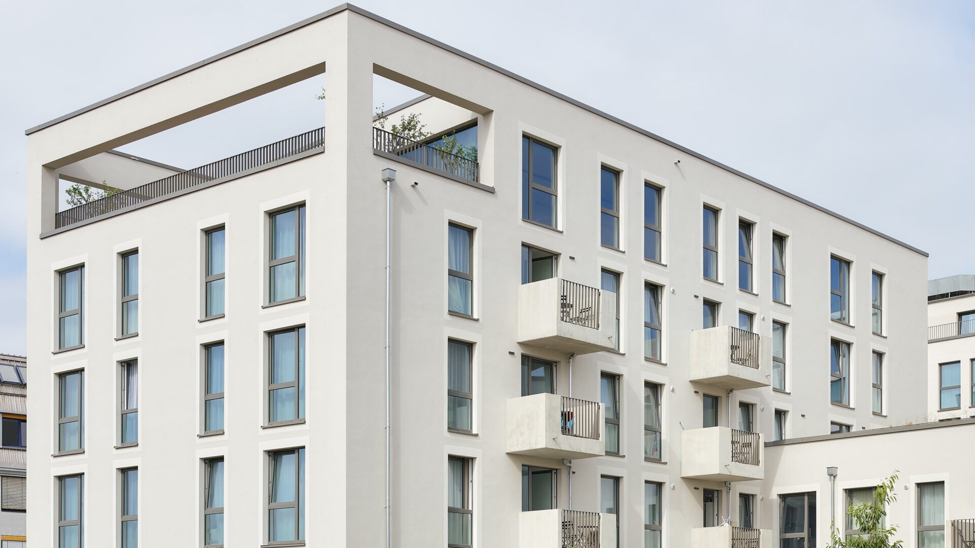 Gebäudeecke des Wohnbaus mit dem auskragenden Rahmen der Dachterrasse