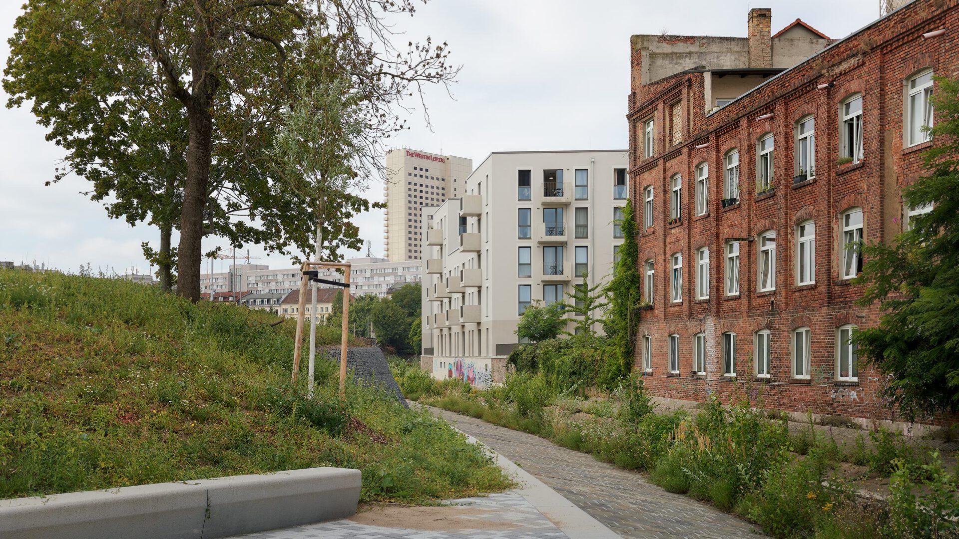 Fußweg zwischen dem alten Backsteinbau und dem hellen Neubau des Quartiers
