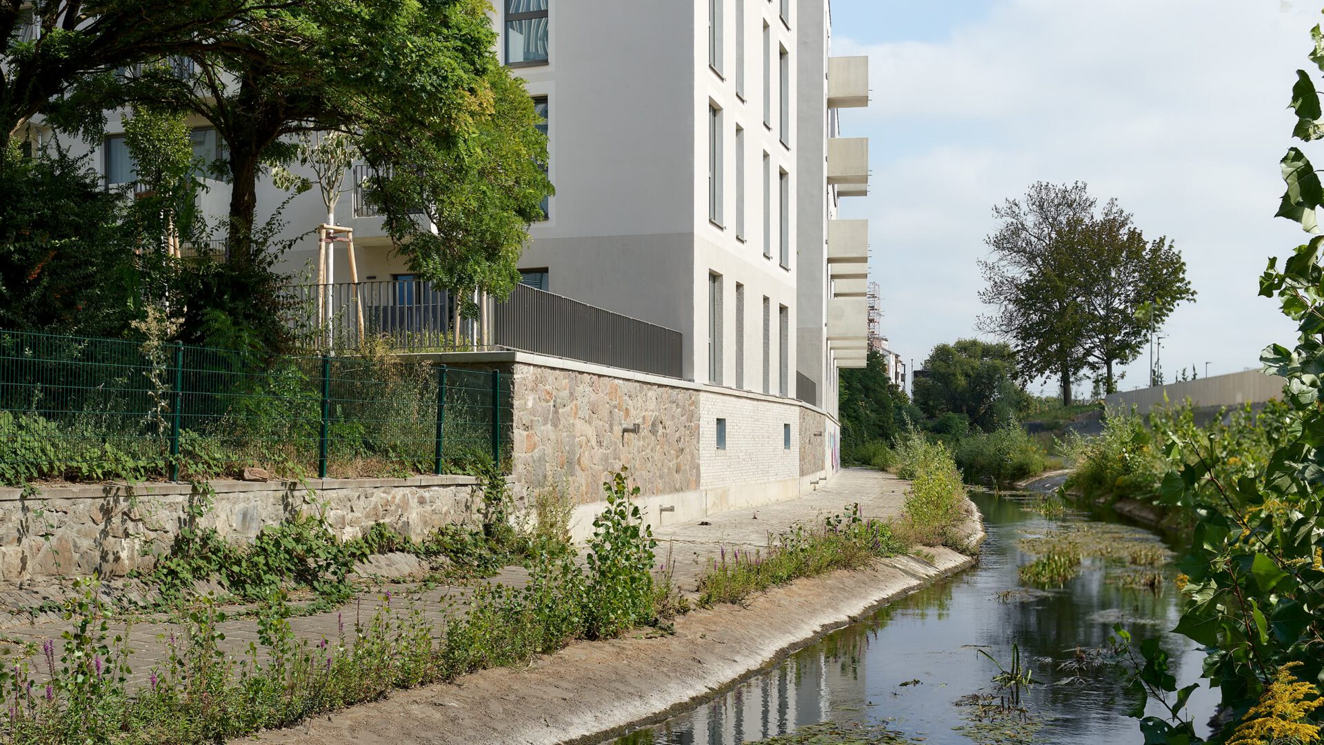 Renaturierter Kanal unmittelbar am Gebäude, mit dichter Uferbepflanzung