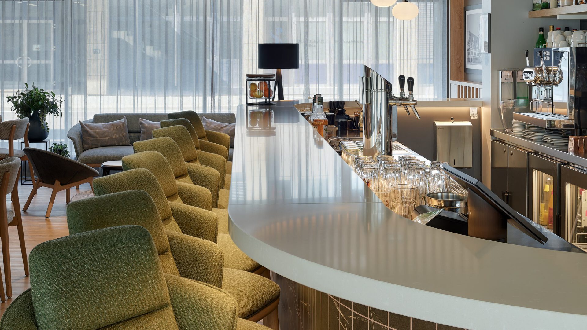 Hotelbar mit grünen Sesseln und geschwungenem Tresen