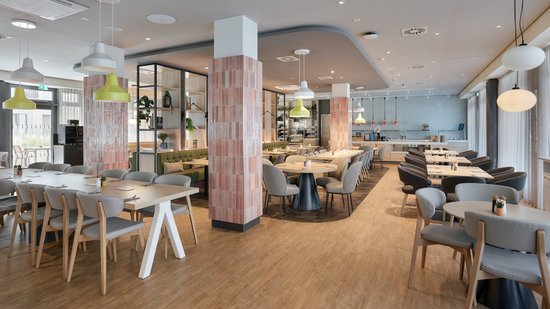 Restaurant mit hellen Holztischen und rosa gefliesten Stützen
