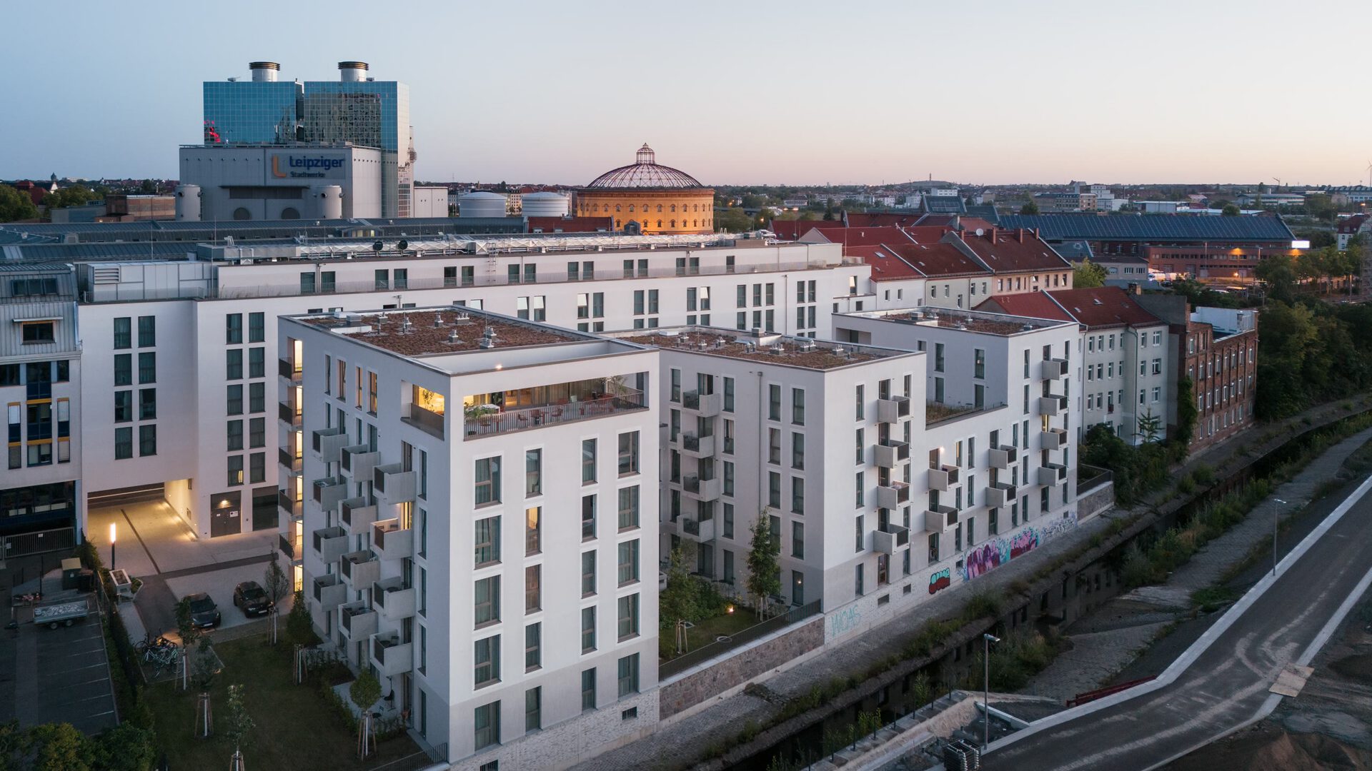 Das Quartier in der Dämmerung, dahinter die Kuppel der Kongresshalle und die Leipziger Innenstadt
