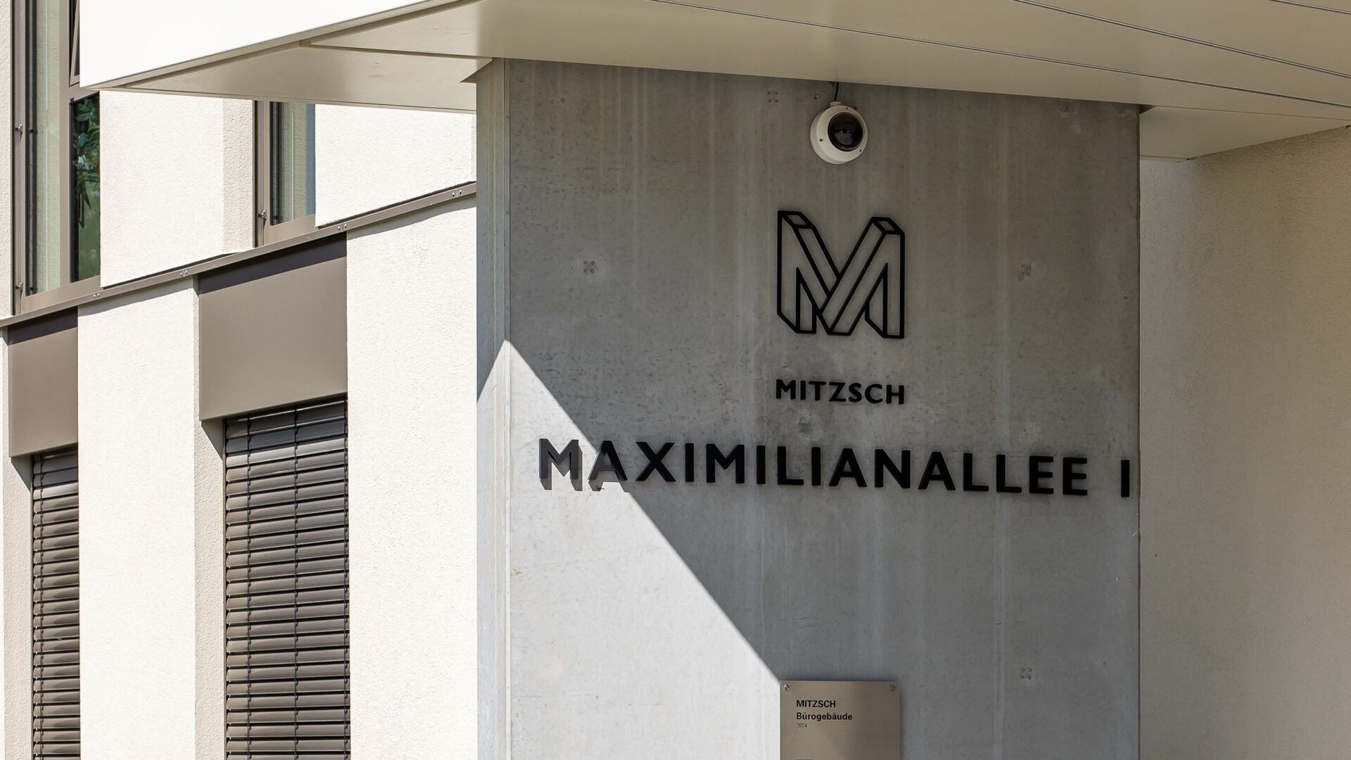 Betonstütze am Eingang von MITZSCH mit Logo und Adresse Maximilianallee I