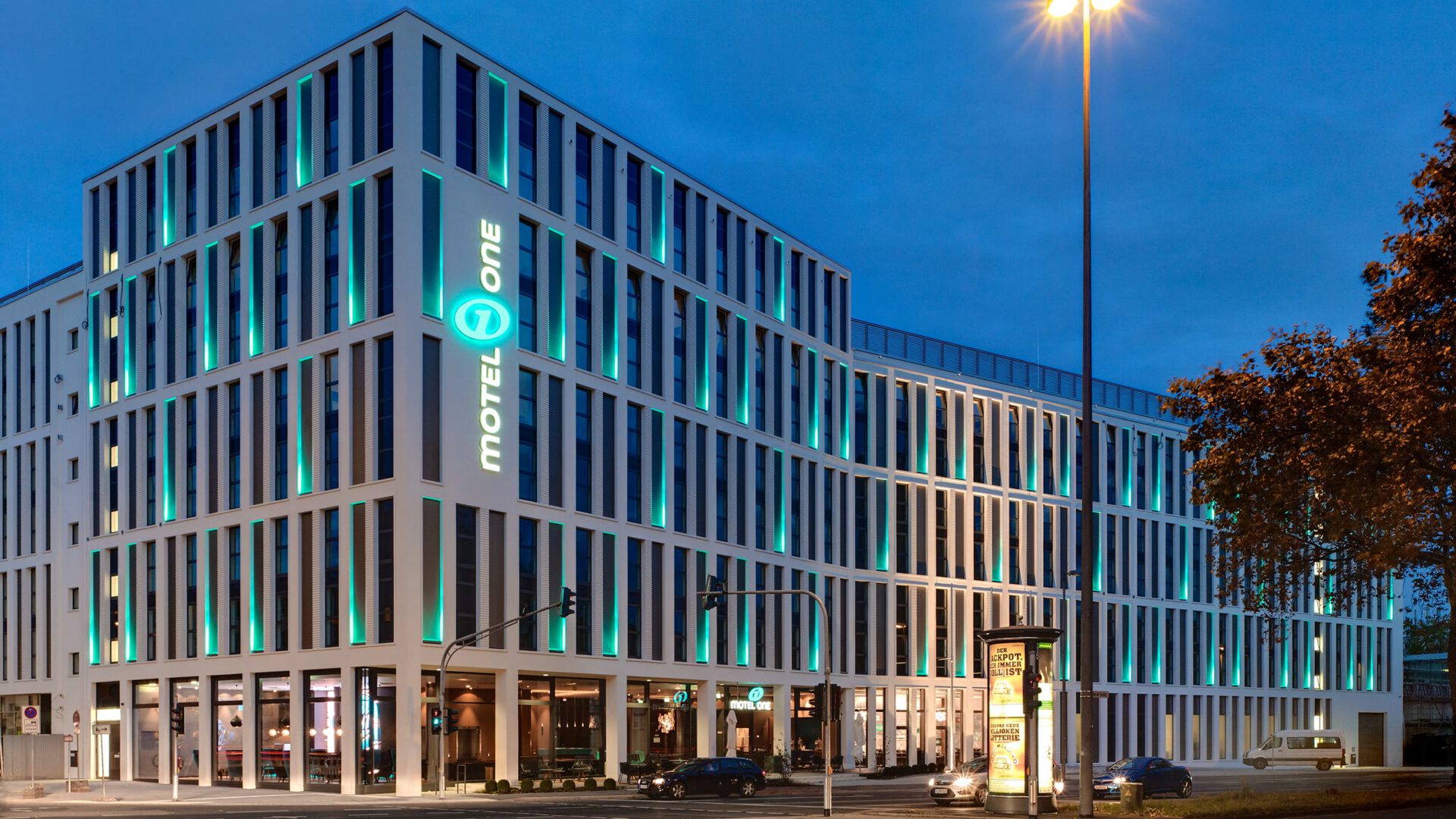 Beleuchtete Gebäudeecke des Motel One in der blauen Stunde