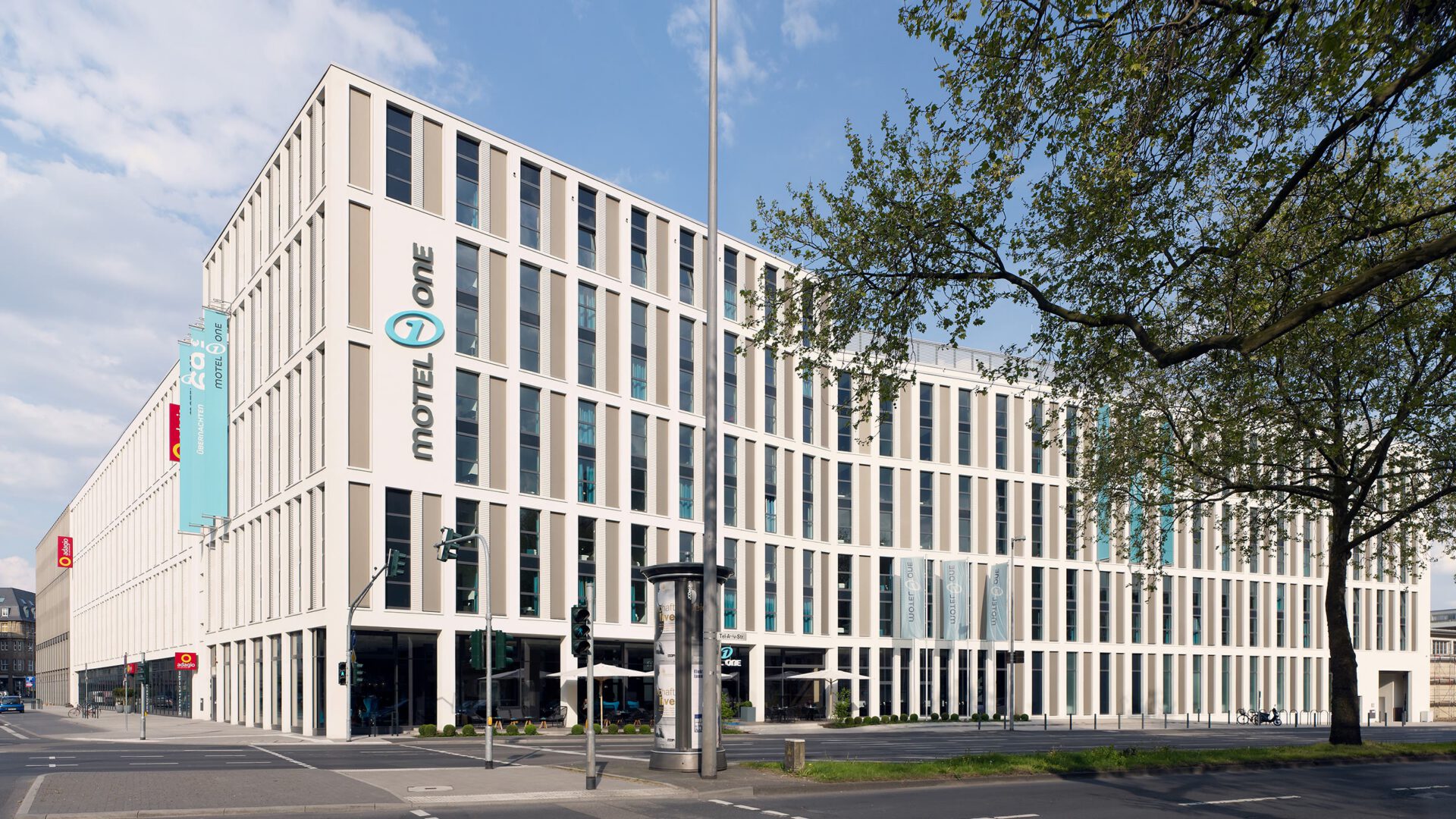 Motel One von der Kreuzung aus mit dem Werbebanner an der Seitenfassade