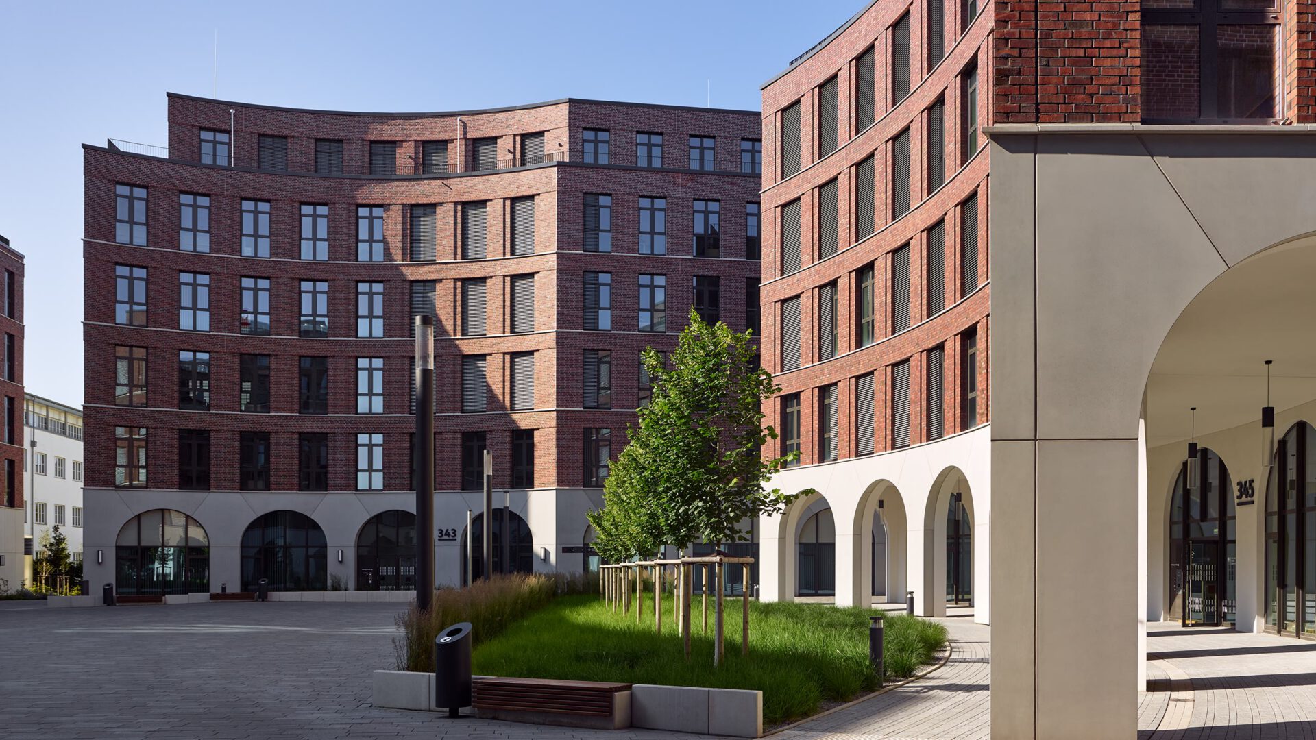 Quartiersplatz von OVUM mit Arkadengang, Baumhain und Gräserbeeten