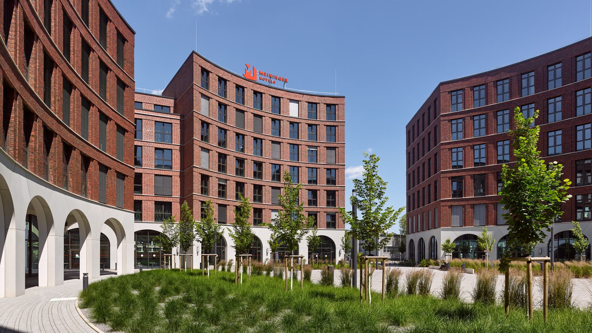 Der Hotelbau von OVUM hinter dem bepflanzten Streifen des Quartiersplatzes